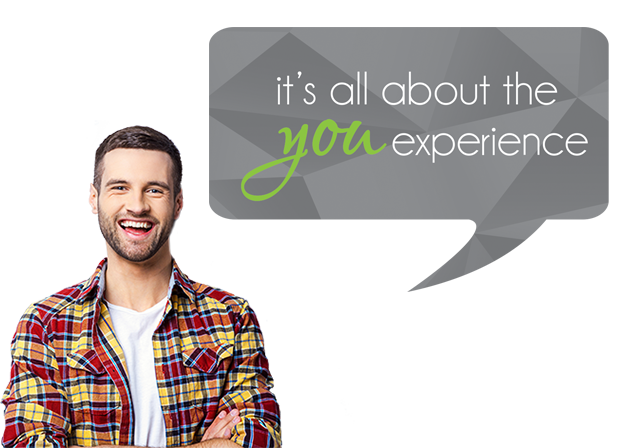 A smiling young bearded male, dressed in a white t-shirt and red, orange, yellow and black plaid shirt, speaking through a gray speech bubble: it's all about the you experience